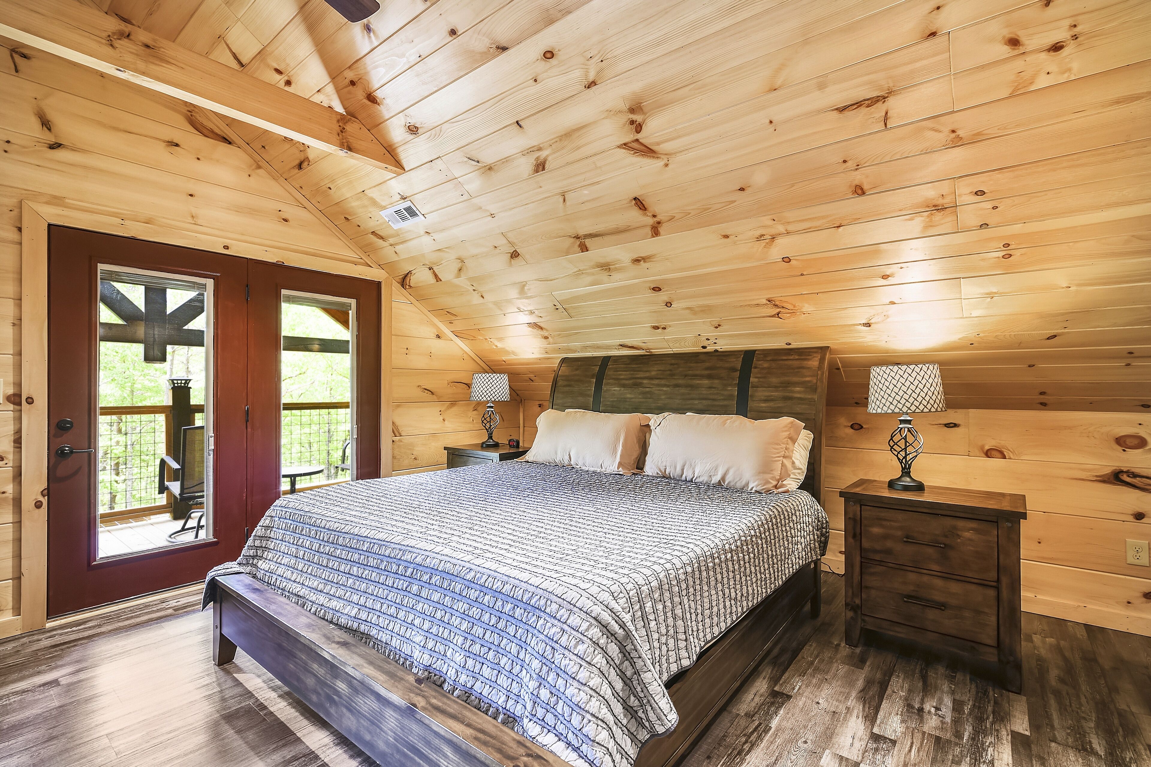 Camera da letto in una baita di legno, con un letto, due comodini e una finestra.