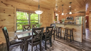 A wooden cabin interior with a dining area, kitchen, and large windows. - All Decked Out 4 Bedroom Cabin by RedAwning (Sevierville)