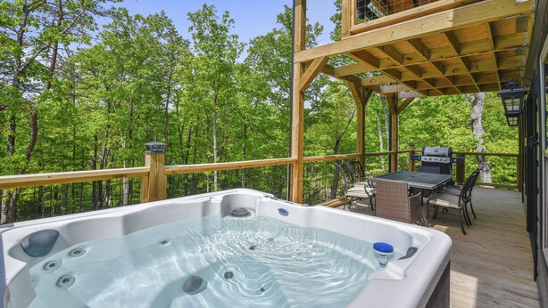 A hot tub on a wooden deck with a view of a forest. - All Decked Out 4 Bedroom Cabin by RedAwning (Sevierville)