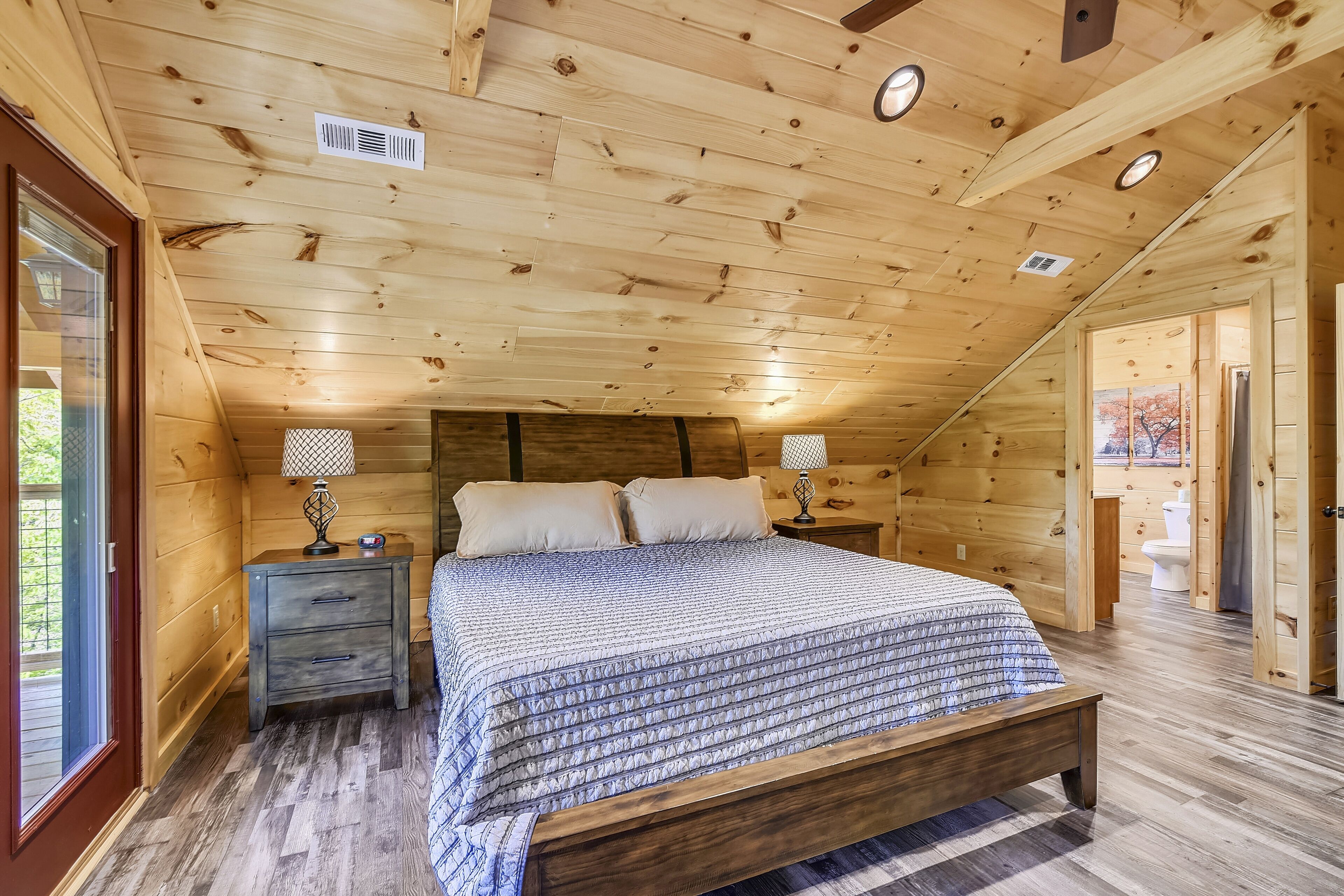 A wooden bedroom with a bed, nightstands, and a window.