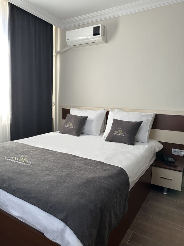 A hotel room with a bed, a bedside table with a phone, and an air conditioning unit mounted on the wall. - Cetinler Hotel (Demirköy)