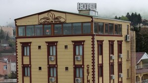 Et hotel i flere etager med gul facade, flere airconditionanlæg og en rød markise over indgangen.