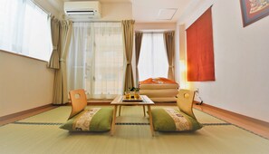 A room with a sofa, two chairs, a small table with glasses, and a wall-mounted air conditioner. - Ukishima Inn (Naha)