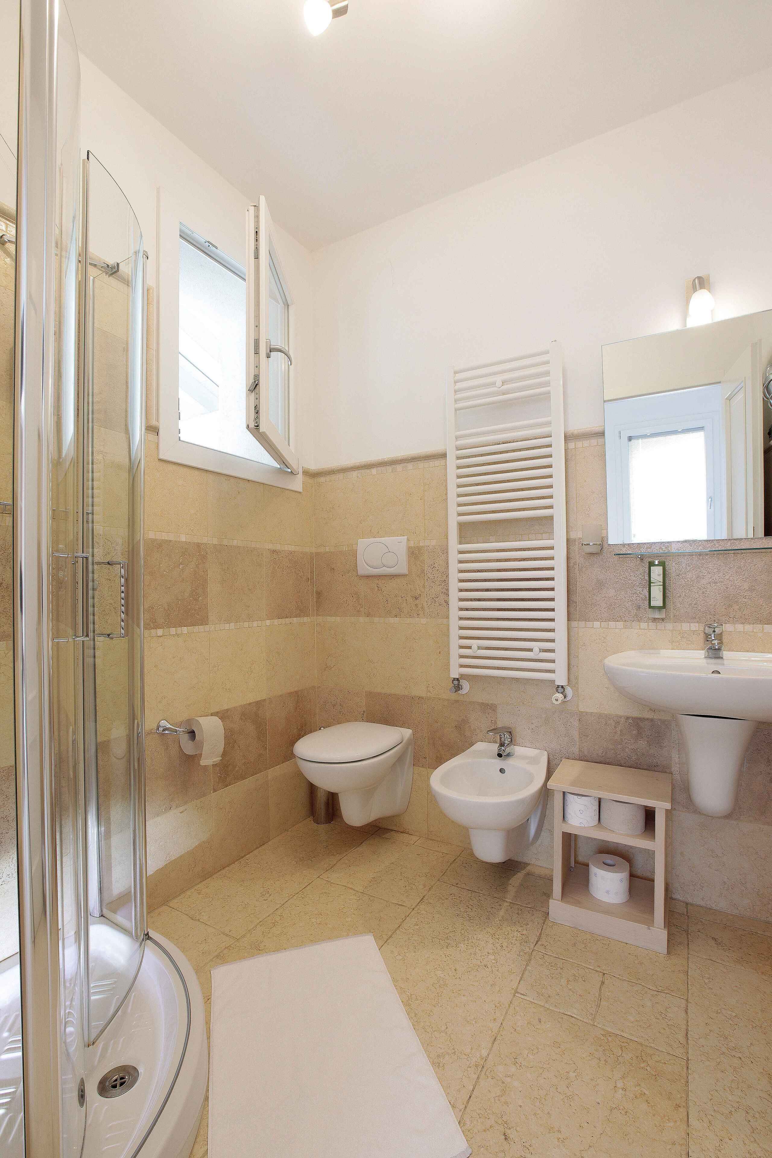 Un baño con cabina de ducha de vidrio, inodoro, bidé, lavamanos y toallero.