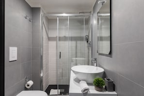 A modern bathroom with a glass-enclosed shower, a white sink, and a mirror.