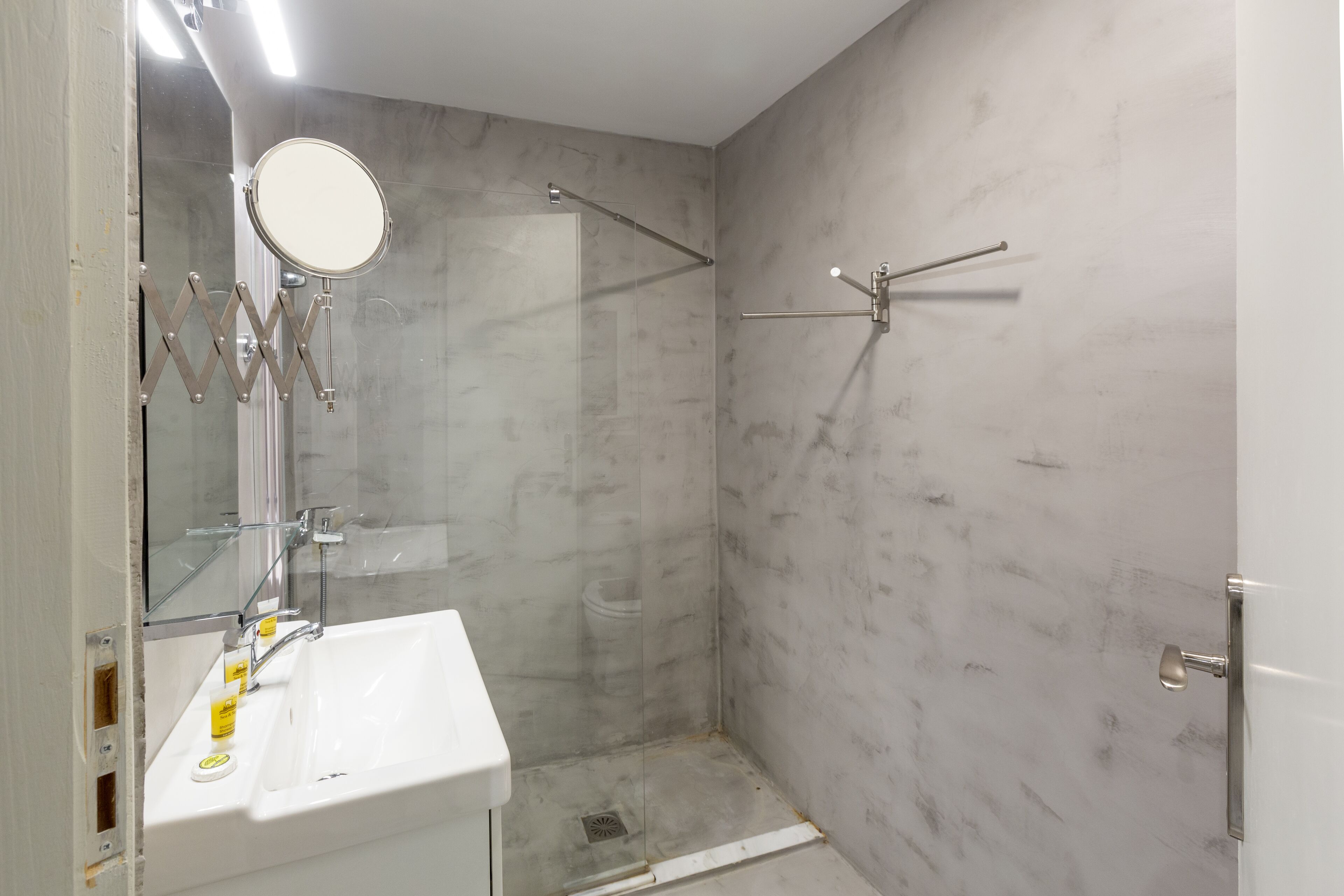 Une salle de bain avec un lavabo blanc, un miroir et une douche.