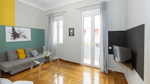 A modern living room with a grey sofa, a glass coffee table, and a flat-screen TV mounted on the wall. - Kavalloti Place (Athens)