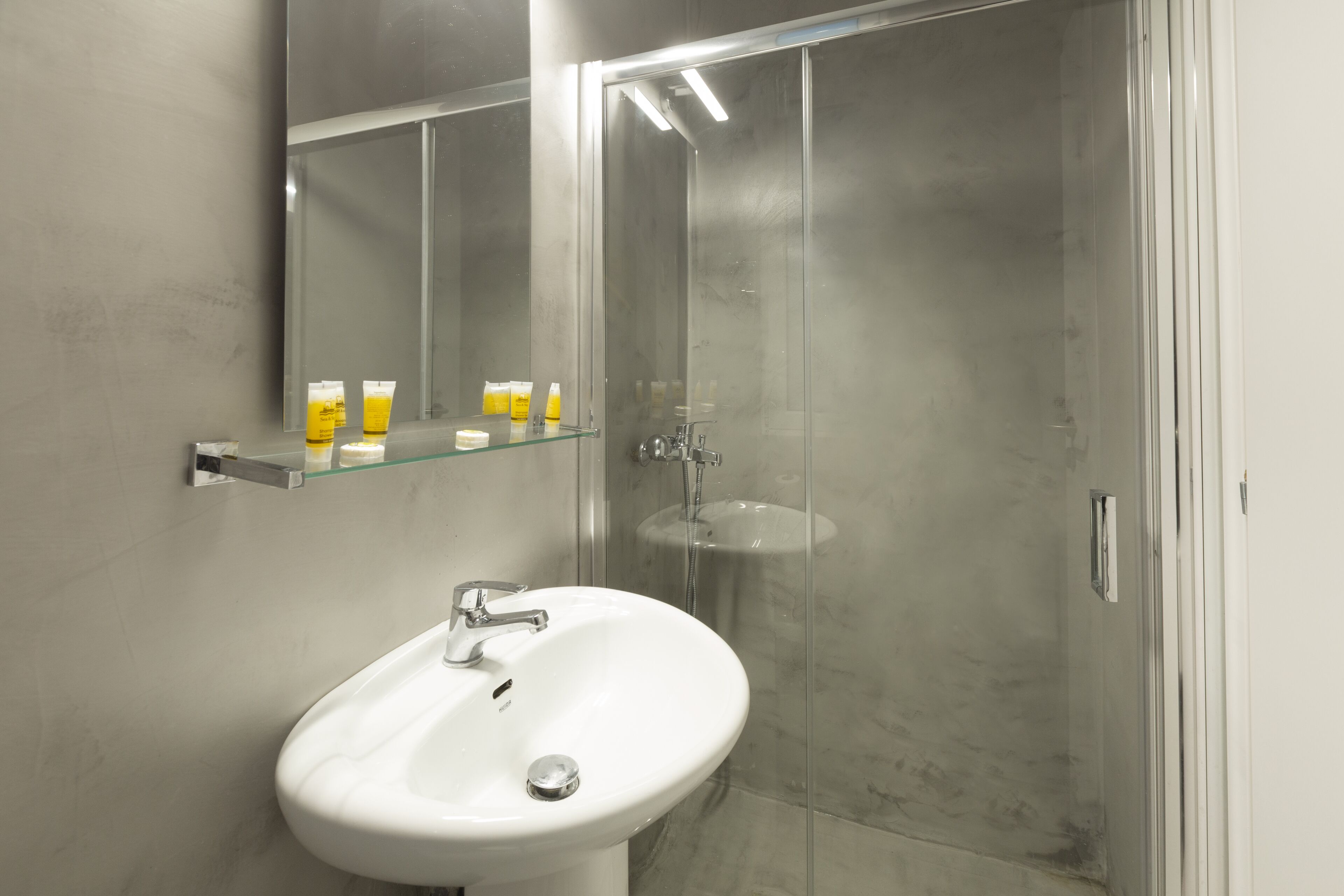 A modern bathroom with a white sink, glass shower enclosure, and a mirror above the sink.
