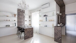 Una cocina moderna con baldosas estampadas, una lámpara de araña y estanterías abiertas con varios objetos.