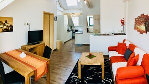 A modern apartment with a dining area, a living room with a sofa, a kitchen, and a skylight. - Schweizerhaus Meissen (Meissen)
