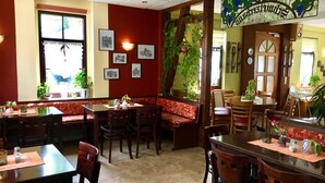A restaurant with wooden tables and benches, framed pictures on the walls, and potted plants. - Schweizerhaus Meissen (Meissen)