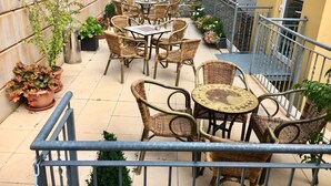 A balcony with wicker furniture, potted plants, and a stone wall. - Schweizerhaus Meissen (Meissen)