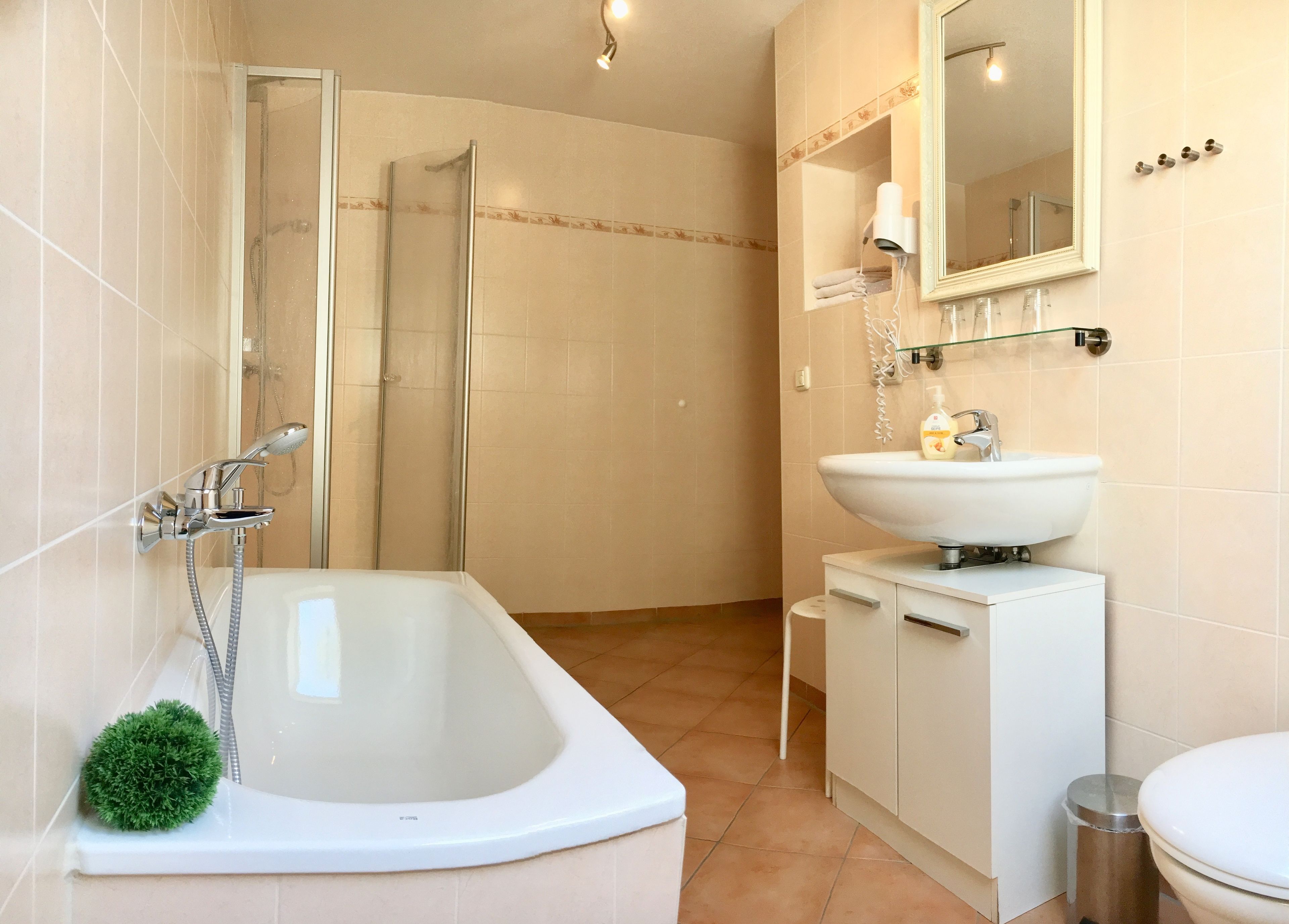 A modern bathroom with a freestanding bathtub, a glass-enclosed shower, a sink with a mirror above, and a toilet.
