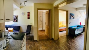 A modern apartment with a kitchen, dining area, and a bedroom with a bed and a baby playpen. - Schweizerhaus Meissen (Meissen)