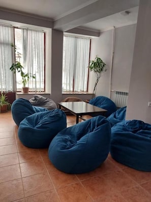 A living room with large bean bags, a small table, and potted plants. - University Hotel Tsakhkadzor (Tsaghkadzor)
