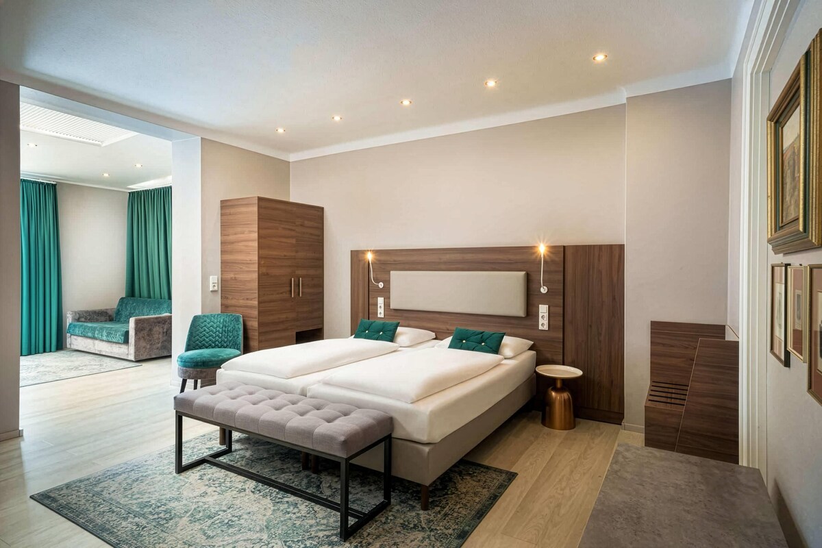 A modern bedroom with a double bed, a bench, a bedside table, and a large window.