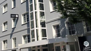 A multi-story hotel with a prominent vertical glass elevator shaft, multiple windows, and a sign indicating it is the Arthotel Ana Liberty. - Arthotel ANA Liberty, Trademark Collection by Wyndham (Bremen)