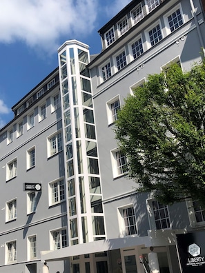 A multi-story hotel with a prominent vertical glass elevator shaft, multiple windows, and a sign indicating it is the Arthotel Ana Liberty. - Arthotel ANA Liberty, Trademark Collection by Wyndham (Bremen)
