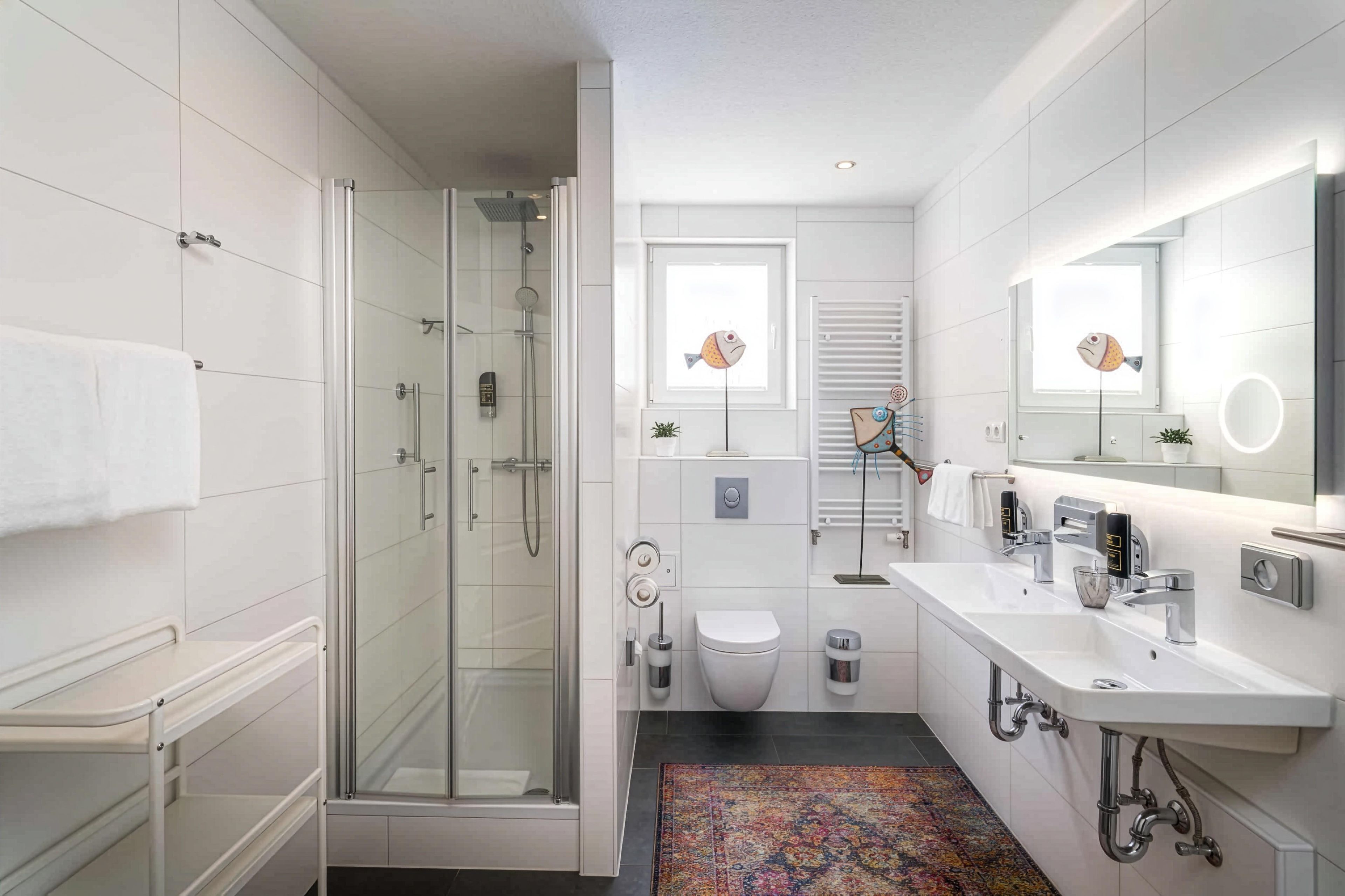 Un baño moderno con ducha envuelta en vidrio, un lavabo blanco con espejo y un inodoro.