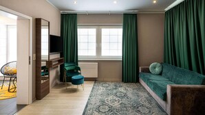 A modern living room with a sofa, a television, a small table, and a chair. - Arthotel ANA Liberty, Trademark Collection by Wyndham (Bremen)