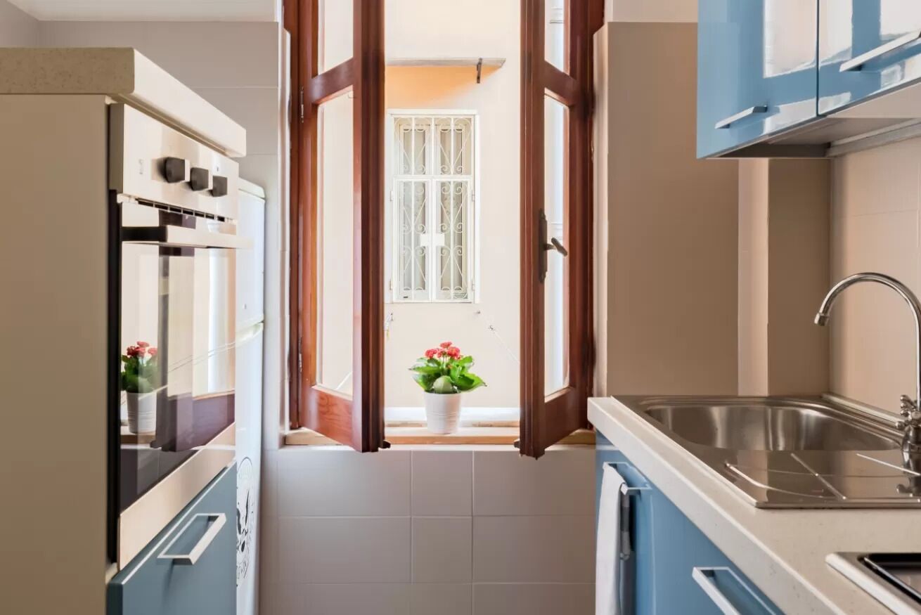 A kitchen with an open door leading to a balcony, a sink, and cabinets.