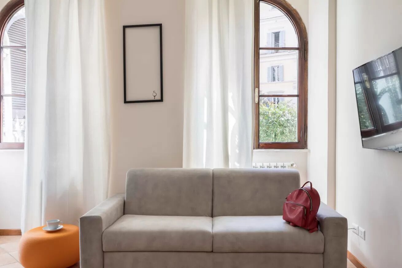 A modern living room with a grey sofa, a red bag, and a framed picture on the wall.