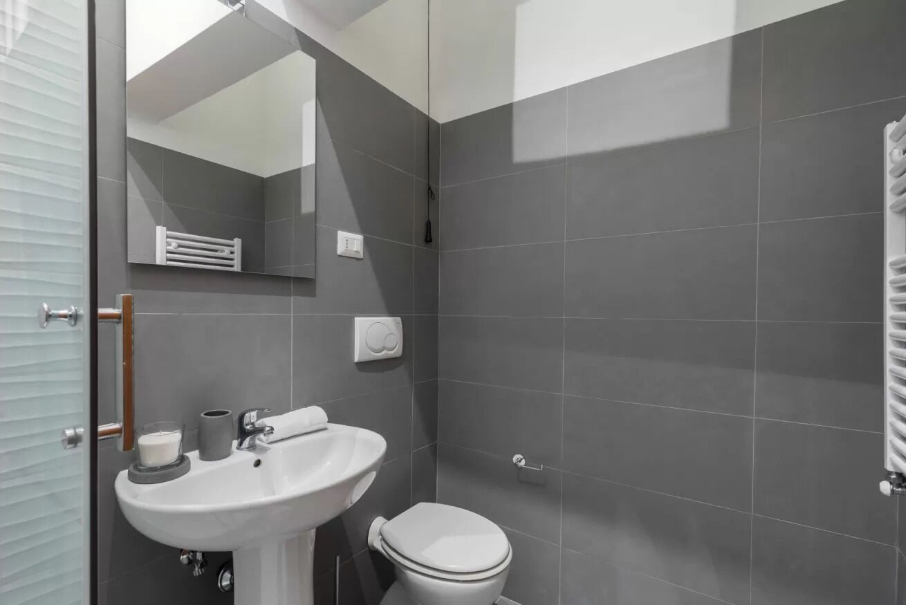 A modern bathroom with a white sink, toilet, and a glass shower enclosure.