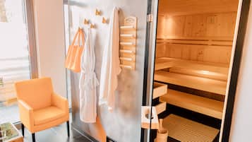 A modern bathroom with a glass shower door, wooden benches, and a seating area with a chair.