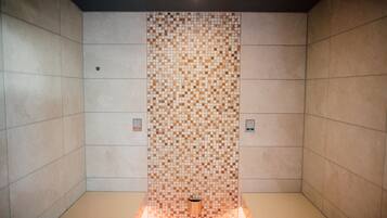 A tiled shower area with a central drain, two flush toilets, and a ceiling light.