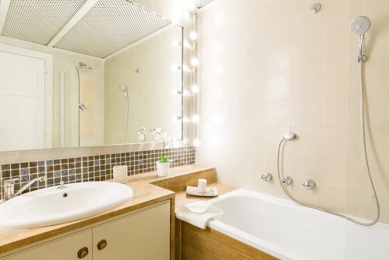 Un baño con lavamanos, espejo, tocador y bañera.