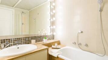 Un baño con lavamanos, espejo, tocador y bañera.