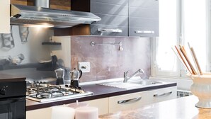 A modern kitchen with a gas stove, stainless steel range hood, and a granite countertop.
