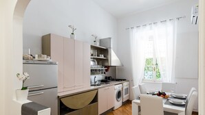 A modern kitchen with a built-in oven, microwave, and sink. There is a dining area with a table and chairs. - A World Aparts - 32 Calabria (Rome)