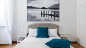 A bedroom with a bed, two nightstands, a white wall, and a framed picture above the bed. - A World Aparts - 32 Calabria (Rome)