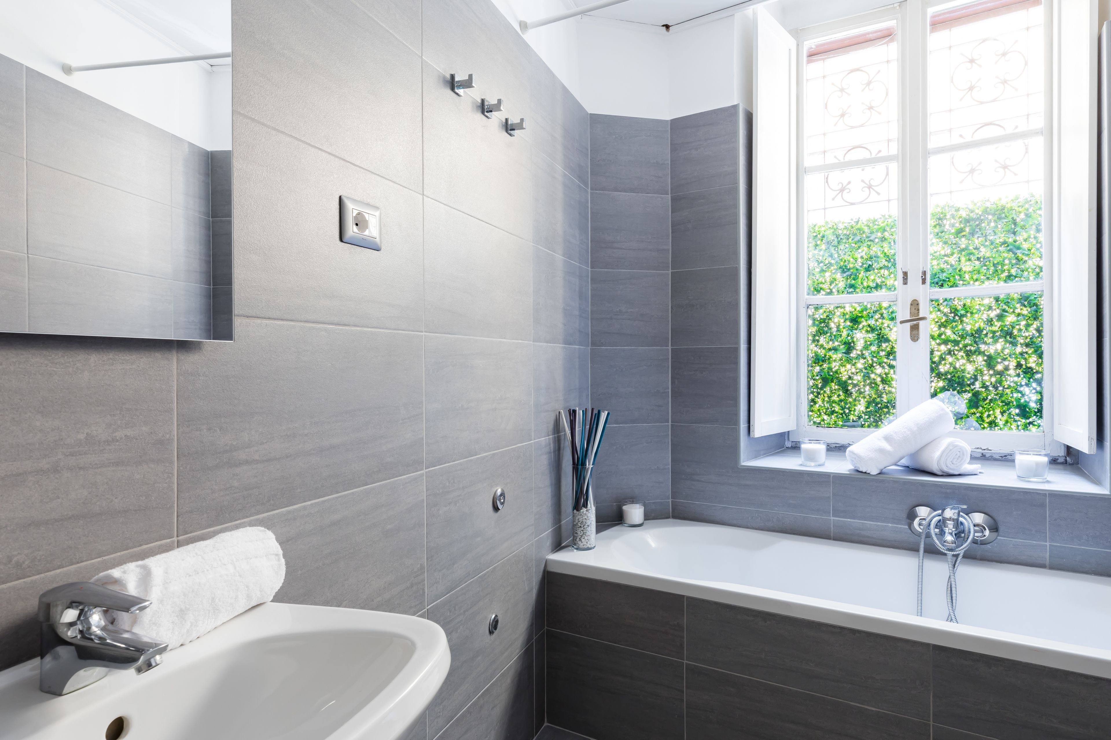 Ein modernes Badezimmer mit Badewanne, einem Fenster mit Blick auf Grünflächen und einem Handtuchhalter.