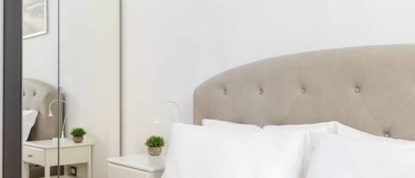 A bedroom with a bed, a nightstand, a mirror, and a dresser.