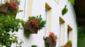 A building with the sign "Transfer München" and flower boxes on the windows. - Rengser Mühle (Bergneustadt)