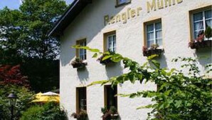 A building with the name "Bergler Mühle" on the facade, surrounded by greenery and a clear sky. - Rengser Mühle (Bergneustadt)
