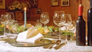 A dining table set with wine glasses, a candle, and a bottle of wine. - Rengser Mühle (Bergneustadt)