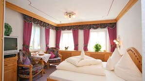A cozy bedroom with a wooden bed, a TV, a dining table, and chairs. - Rengser Mühle (Bergneustadt)