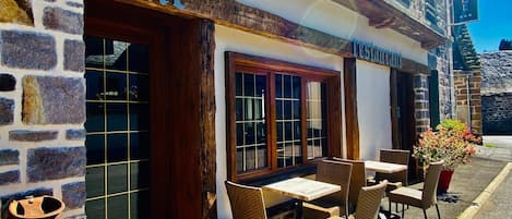 A restaurant with outdoor seating, stone walls, and wooden beams.
