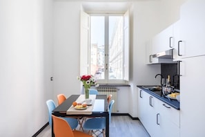 Una cocina compacta con comedor, una ventana que ofrece vistas a edificios y una pequeña mesa con sillas.