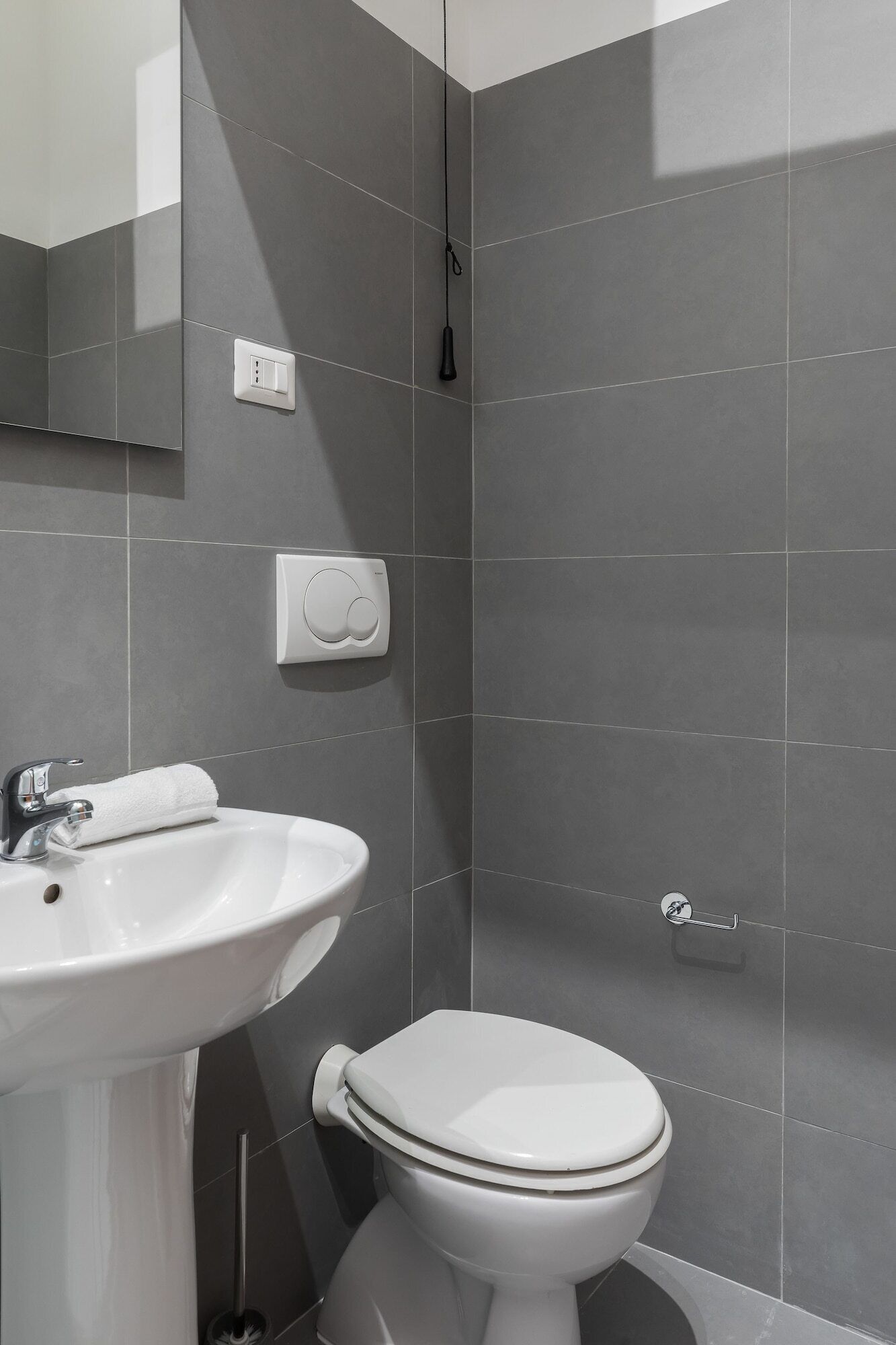 Un baño con lavamanos blanco, inodoro y espejo.