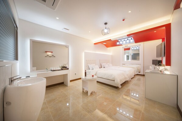 A modern hotel room with a large bed, a separate bathroom, a vanity with a mirror, and a small seating area. - Samho Hotel (Yeongam)