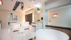 Un baño de hotel moderno con una bañera grande, zona de ducha separada y tocador con espejo.