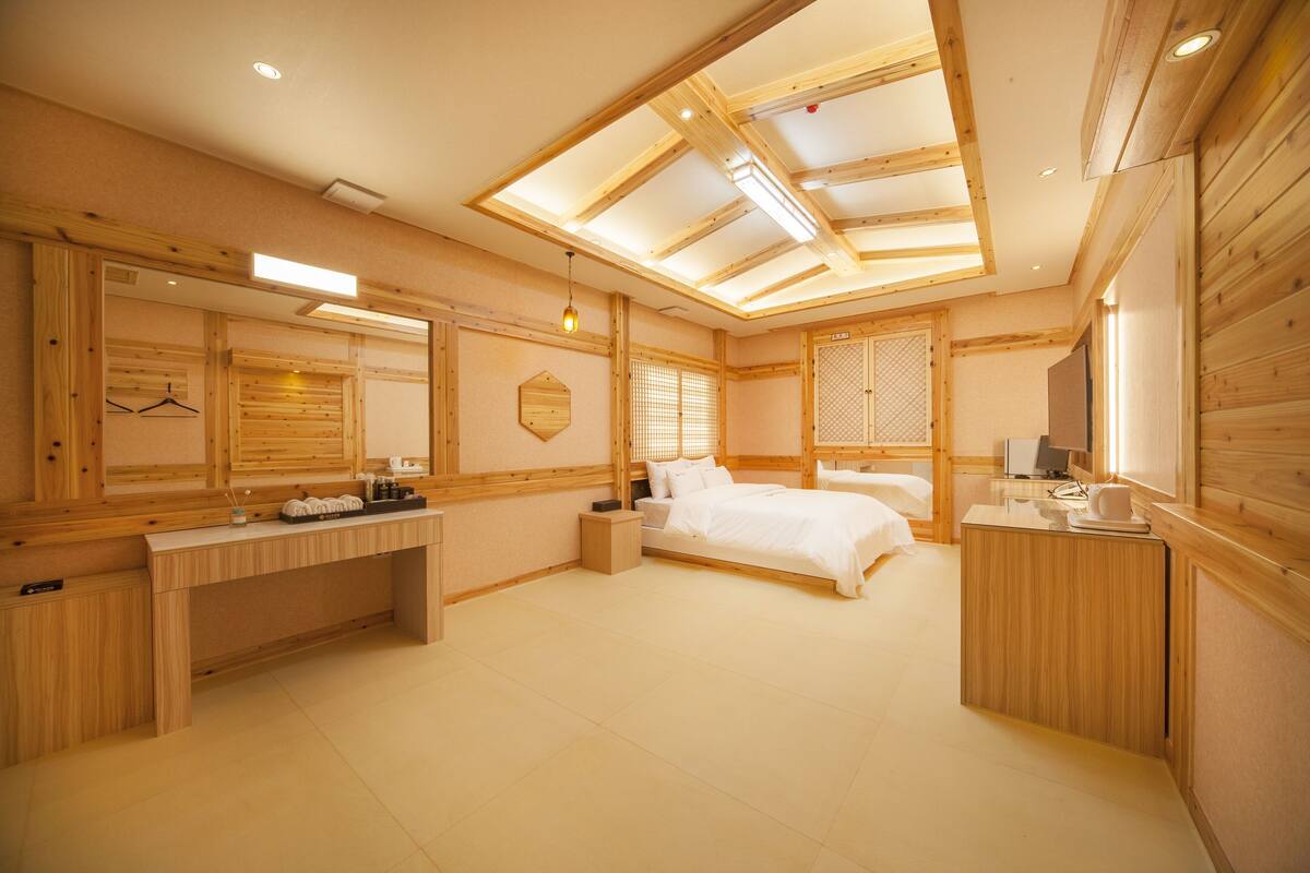 A hotel room with a wooden interior, a bed, a desk, and a television.