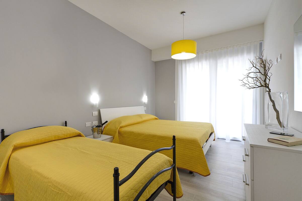A hotel room with two beds, a desk, and a chair.