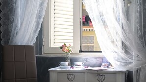 A small white table with a vase of flowers, two cups, and a book. - Voglia di Napoli (Naples)