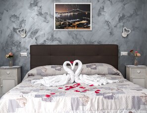 A bedroom with a bed, two nightstands, a wall-mounted picture, and heart-shaped decorations. - Voglia di Napoli (Naples)