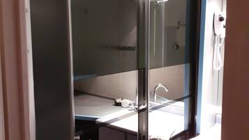 A bathroom with a glass-enclosed shower, a sink, and a mirror.